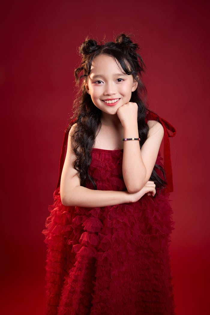 Portrait of a smiling Asian girl in a red dress against a matching background in Ho Chi Minh City.