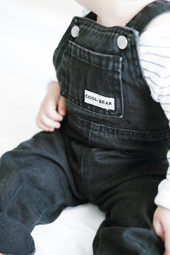 Adorable baby wearing stylish black denim overalls with 'Cool Bear' label.